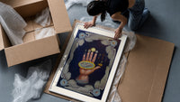 Upraised hand with alchemical symbols framed print being unpacked from protective bubble wrap and a box
