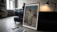 Ancient Greek philosopher holding pyramid print in a slim black frame leaning on a dark sofa in a concrete print studio