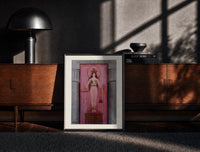 Black-framed Egyptian goddess Isis unveiled print on a moody console with designer coffee-table books