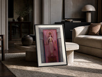 Egyptian goddess Isis unveiled print in a black frame leaning on a travertine table in a sunlit lounge