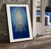 Meditating figure with chakra symbols print in a black frame leaning beside a vintage door on parquet