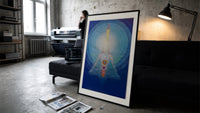 Meditating figure with chakra symbols print in a slim black frame leaning on a dark sofa in a concrete print studio