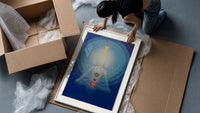 Meditating figure with chakra symbols framed print being unpacked from protective bubble wrap and a box
