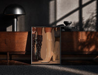 Black-framed Knee-High Boots in Black and Beige print on the floor in front of a dark wooden console