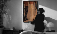 Knee-High Boots in Black and Beige print in a slim black frame being hung on a sunlit wall in a monochrome room