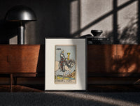 Black-framed Knight riding horse holding cup print on a moody console with designer coffee-table books