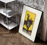 Knight on horse holding pentacle poster in a black frame leaning beside a shelf in a raw-plaster loft