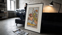 Knight riding horse holding wand print in a slim black frame leaning on a dark sofa in a concrete print studio