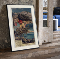 French Riviera coastal railway scene print in a black frame leaning beside a vintage door on parquet