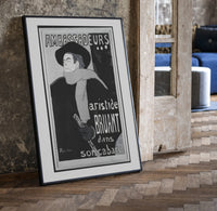 Man in hat and scarf print in a black frame leaning beside a vintage door on parquet