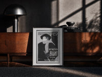 Black-framed Man in hat and scarf print on a moody console with designer coffee-table books
