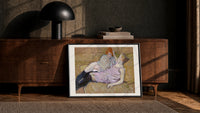 Two reclining women on sofa print in a black frame leaning against a walnut console in lamplight