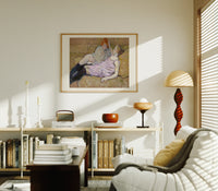 Two reclining women on sofa print in an oak frame above a mid-century book console with a vintage radio