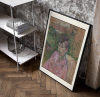 Woman in pink dress portrait poster in a black frame leaning beside a shelf in a raw-plaster loft
