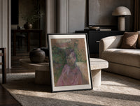 Woman in pink dress portrait print in a black frame leaning on a travertine table in a sunlit lounge