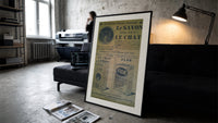 Vintage French soap advertisement with cat print in a slim black frame leaning on a dark sofa in a concrete print studio