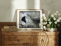 Woman's face with flowing hair reclining print in an oak frame on a farmhouse dresser beside white tulips