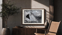 Woman's face with flowing hair reclining print in a wood frame above a fluted sideboard beside an olive tree