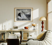 Woman's face with flowing hair reclining print in an oak frame above a mid-century book console with a vintage radio