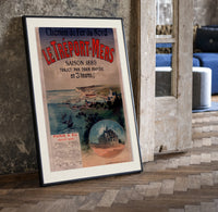 Coastal seaside town harbour view print in a black frame leaning beside a vintage door on parquet