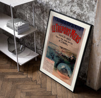 Coastal seaside town harbour view poster in a black frame leaning beside a shelf in a raw-plaster loft