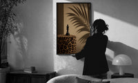 Leopard Print Chess King print in a slim black frame being hung on a sunlit wall in a monochrome room