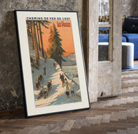 Winter sports scene with sledders and skiers print in a black frame leaning beside a vintage door on parquet