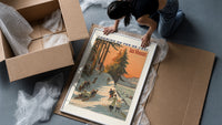 Winter sports scene with sledders and skiers framed print being unpacked from protective bubble wrap and a box