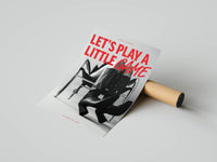 Let's Play a Little Game poster being unrolled on a concrete floor
