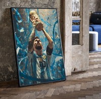 Footballer lifting World Cup trophy print in a black frame leaning beside a vintage door on parquet