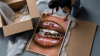 Lips Holding a Daddy Chain framed print being unpacked from protective bubble wrap and a box