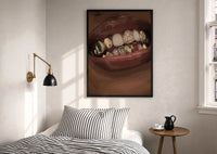 Lips with Decorative Gold Grillz print in a black frame above a bed with striped linens