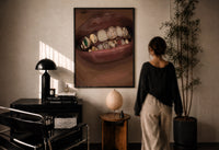 Lips with Decorative Gold Grillz print in a black frame on a sunlit plaster wall, a woman looking on beside a mushroom lamp