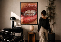 Rows of Tooth Gems print in a black frame on a sunlit plaster wall, a woman looking on beside a mushroom lamp