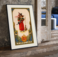 Girl witch holding black cat print in a black frame leaning beside a vintage door on parquet