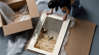 Robin perched on bare branch framed print being unpacked from protective bubble wrap and a box