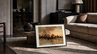 Winter landscape with ice skaters at dusk print in a slim black frame leaning on a travertine coffee table