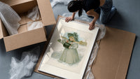 Blonde girl in plumed hat holding violets framed print being unpacked from protective bubble wrap and a box