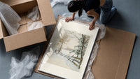 Hunter and dog in snowy landscape framed print being unpacked from protective bubble wrap and a box