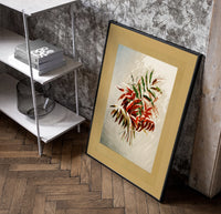 Autumn-tinted leaves branch poster in a black frame leaning beside a shelf in a raw-plaster loft