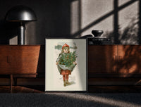 Black-framed Girl carrying holly branches in apron print on a moody console with designer coffee-table books