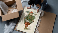Girl carrying holly branches in apron framed print being unpacked from protective bubble wrap and a box