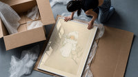 Child in white winter coat and bonnet framed print being unpacked from protective bubble wrap and a box