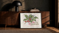 Holly sprig with red berries print in a black frame leaning against a walnut console in lamplight