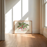 Holly sprig with red berries print in an oak frame on a sunlit wood floor beneath tall window light