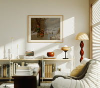 Two children with sled on ice print in an oak frame above a mid-century book console with a vintage radio