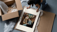 Two Victorian women looking at painting framed print being unpacked from protective bubble wrap and a box