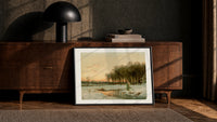 Winter landscape with frozen stream print in a black frame leaning against a walnut console in lamplight