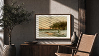 Winter landscape with frozen stream print in a wood frame above a fluted sideboard beside an olive tree