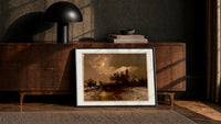 Moonlit winter church landscape print in a black frame leaning against a walnut console in lamplight